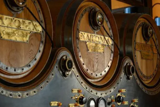 Vintage wooden barrels with brass labels and gauges on a brewery wall.