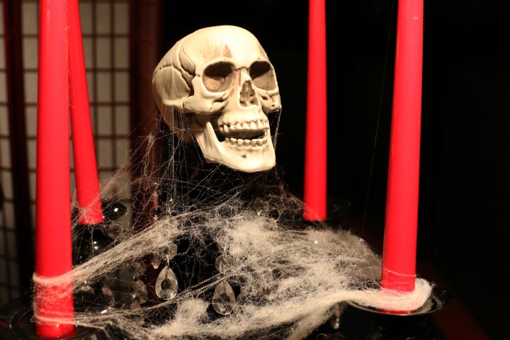 Skull and red candles with cobwebs on a black stand for Halloween decor.