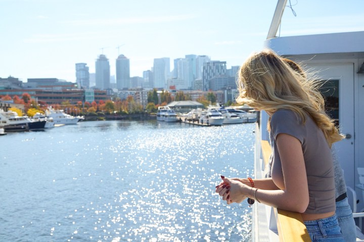 a woman standing in a body of water with a city in the background