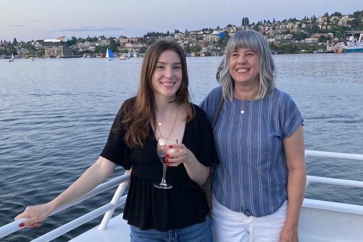 a person standing next to a body of water posing for the camera