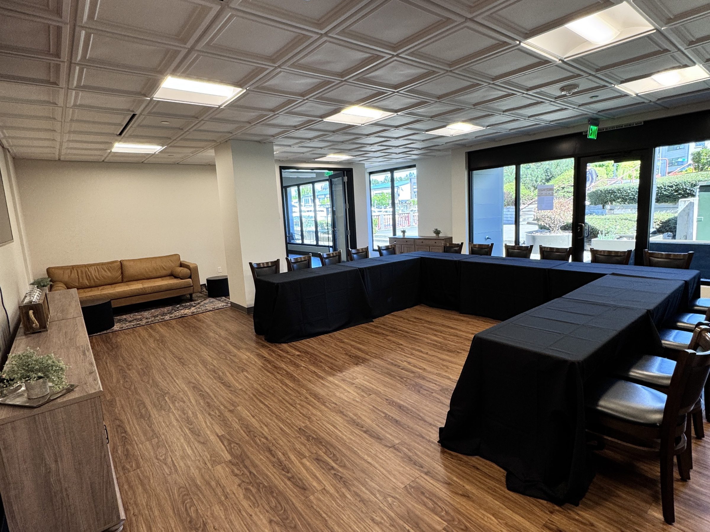 Meeting room with brown floor, black tablecloths, and a beige sofa in the corner.