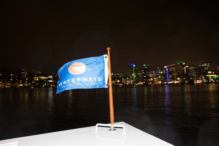 Boat flag with city lights reflecting on water at night.